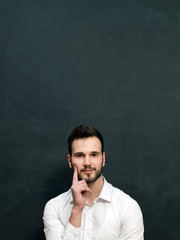 Portrait of a serious young man standing against chalkboard