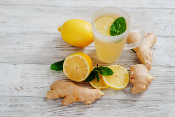 
Herbal tea with lemon , mint and ginger on a white wooden background