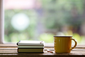 Notebook and yellow cup on wooden table