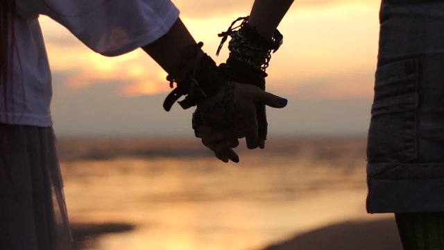 lesbians holding hands at sunset on the beach
