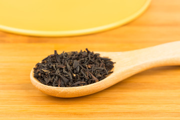 Tea leaves in wooden spoon on wooden background