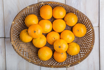 Basket with fresh tangerines on white wooden table