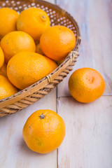 Basket with fresh tangerines on white wooden table