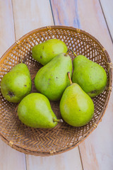 Wicker basket with pears on white wooden table