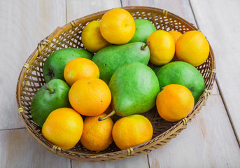 Fresh pears and tangerines in wicker basket on white table