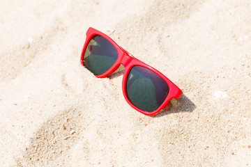 Fototapeta na wymiar Red sun glasses on sand at beach