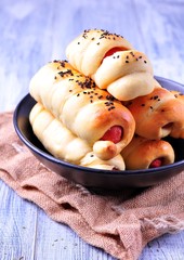 sausage baked in pastry in a black plate on a light wooden background