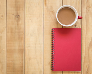 Top view of red book and coffee cup on wooden table