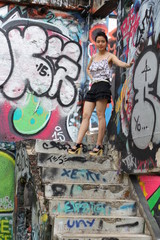 Obraz na płótnie Canvas Portrait of thai adult beautiful girl relax and smile on graffiti wall 
