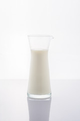 Fresh milk in a glass jug on a white background.