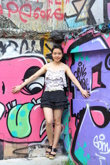 Portrait of thai adult beautiful girl relax and smile on graffiti wall