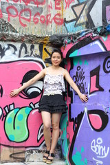 Portrait of thai adult beautiful girl relax and smile on graffiti wall