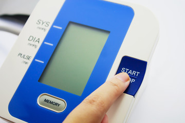 Finger pressing button of digital Blood Pressure Monitor on Whit