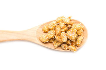 Crispy sugared nuts with wooden spoon isolated on white.