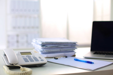 Laptop with stack of folders on table on white background