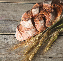 rustic crusty bread and wheat ears on a dark wooden table