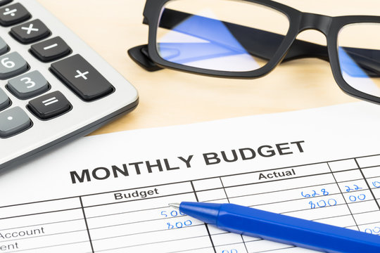 Home budget planning sheet with pen, glasses, and calculator