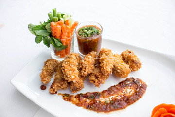 Tasty fried chicken  and vegetable in white plates on white back