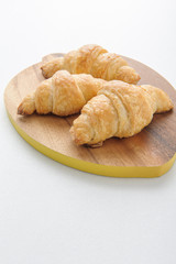 Croissant on wooden plate.