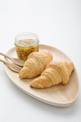 croissant served on white square plate with passion fruit jam
