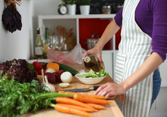 Young woman mixing fresh salad ,oil recharge