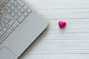 Lap top computer and heart on wooden white table - love technology concept