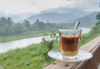 Cup of hot tea and croissant on balcony with mountains behind