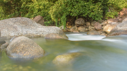 Naklejka na ściany i meble River and forrest rocks with visible movement and blur of the wa