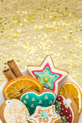 gingerbread cookies and spices in bowl over golden background