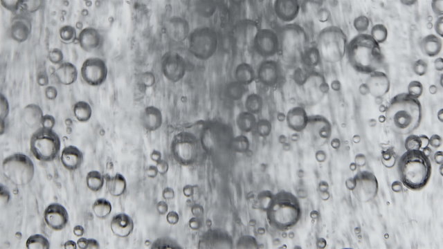Sparkling bubbles rising in a glass of clean water.  Macro close-up 4K.