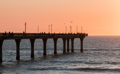 People are  fishing on a pier  at sunrise