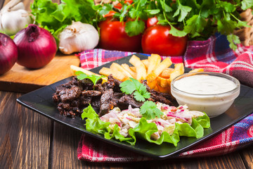 Kebab of beef with french fries and salad