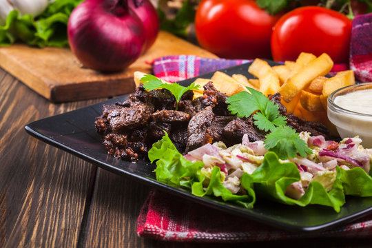 Kebab of beef with french fries and salad