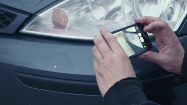 The man photographs on phone scratches by car