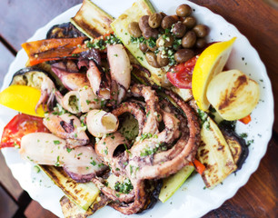The big octopus on a white plate with vegetables, selective focus
