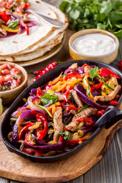 Pork fajitas with onions and colored pepper, served with tortillas.