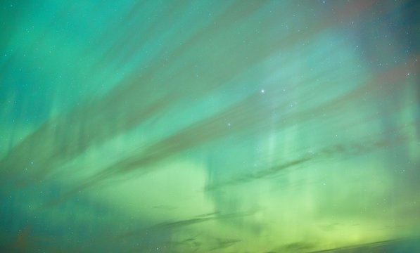 Vibrant colors of the northern lights (Aurora Borealis) dancing in the night sky in Finland. Abstract nature background with green tones.