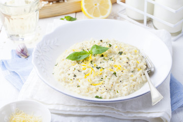 Risotto with lemon and fresh basil. White wooden background