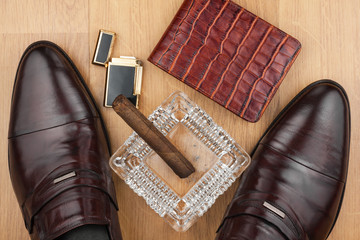 Male still life, classic men's shoes and a cigar in an ashtray