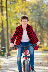 Urban biking - teenage boy riding bike in city park 