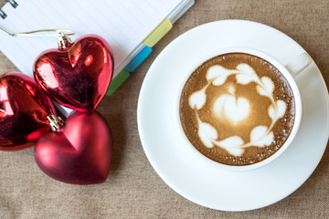 Hot coffee latte, latte art with red heart in white cup on a tab