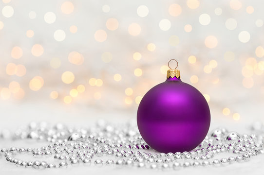 Purple Christmas ball with metallic beads. Bokeh with glow effect on white background. Copyspace for your greeting or wishes