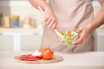 Young tough guy is mixing a salad.
