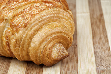 Closeup shot of classic French croissant on wooden table. Studio shot.