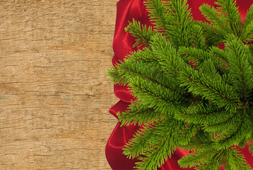 Red cloth with fir tree branch over wooden texture close-up
