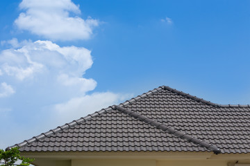 Fototapeta na wymiar black tile roof of house with blue sky and cloud background