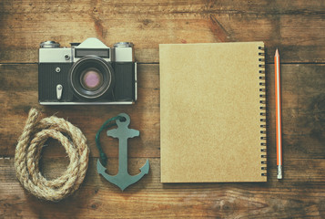 top view image of blank notebook, wooden sailboat, nautical rope and camera. travel and adventure concept. retro filtered image
