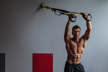 Muscular guy and suspension straps