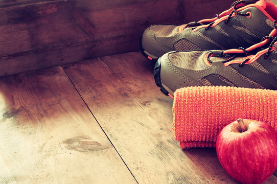 fitness concept with towel, apple and sport footwear over wooden background. retro filtered
