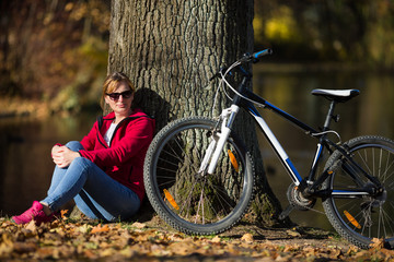 Naklejka na ściany i meble Urban biking - woman and bike in city park